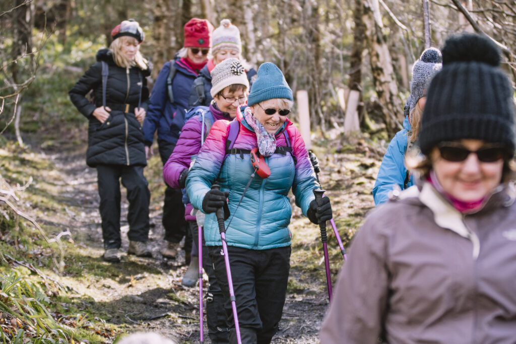 Female club hiking for a body positivity campaign. They are wearing back packs and waterproof clothing.